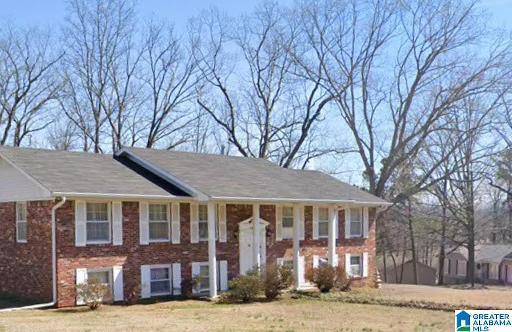 raised ranch with a front yard and brick siding