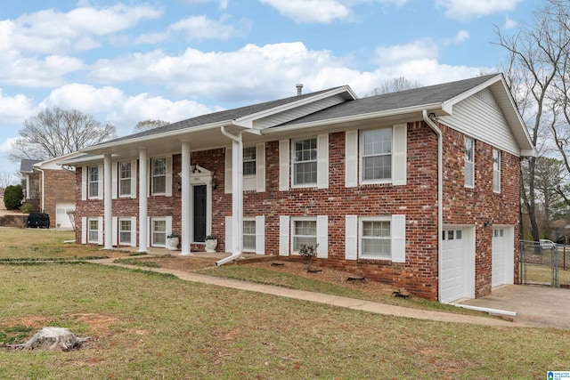 bi-level home with a front yard, fence, driveway, an attached garage, and brick siding