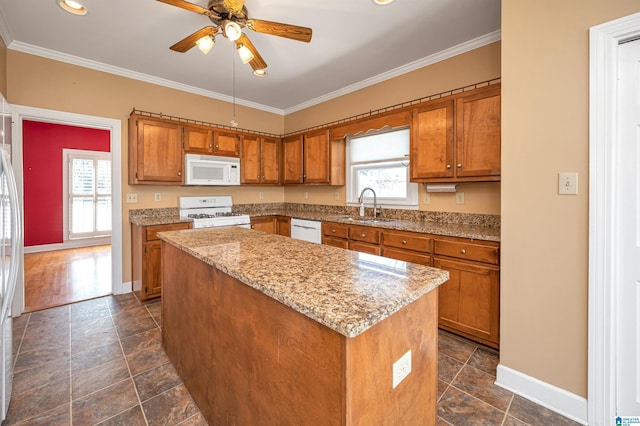 kitchen featuring white appliances, a kitchen island, brown cabinets, and a sink