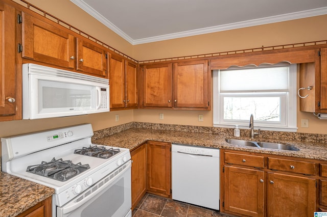 kitchen featuring dark stone countertops, white appliances, brown cabinetry, ornamental molding, and a sink