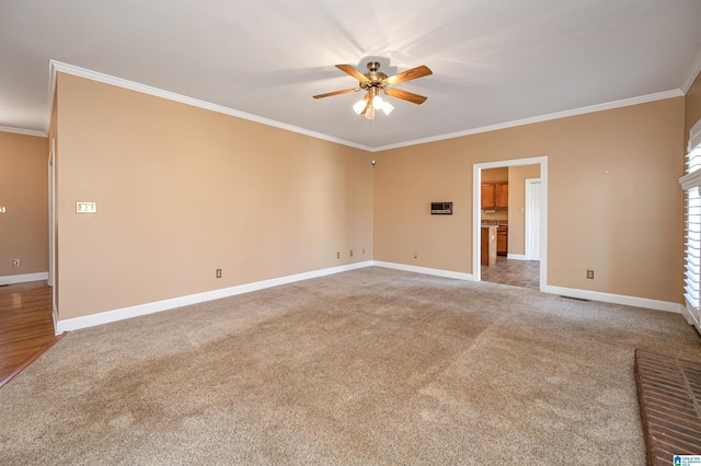 spare room with baseboards, carpet floors, ornamental molding, and a ceiling fan