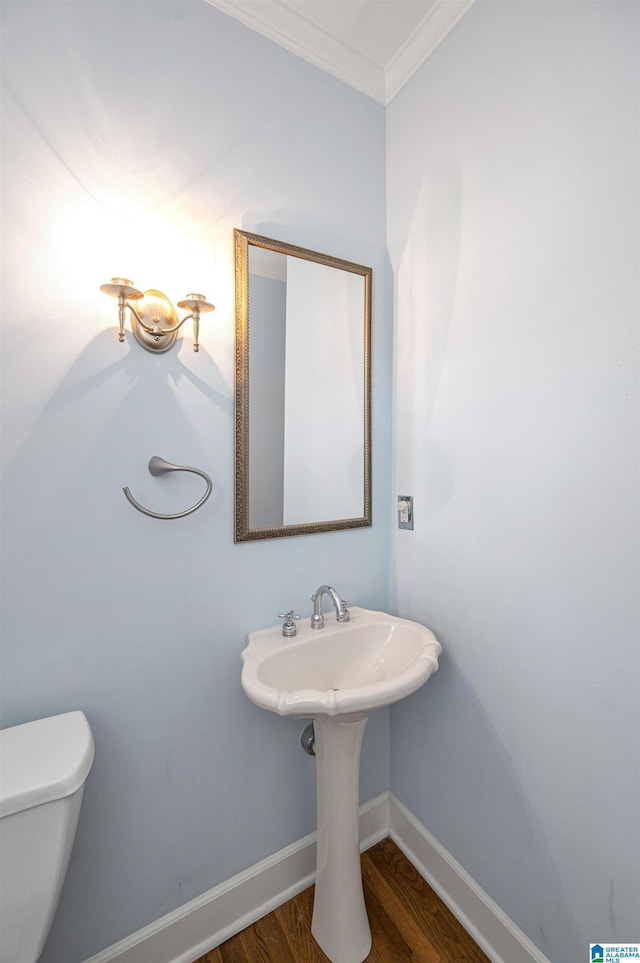 bathroom featuring baseboards, toilet, wood finished floors, and crown molding