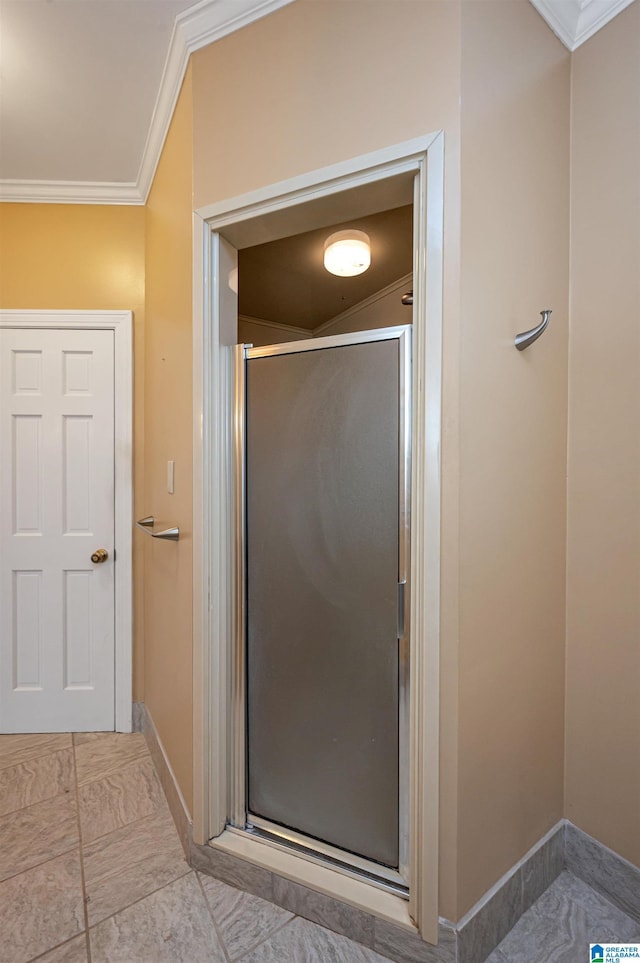 bathroom with a shower stall, crown molding, and baseboards