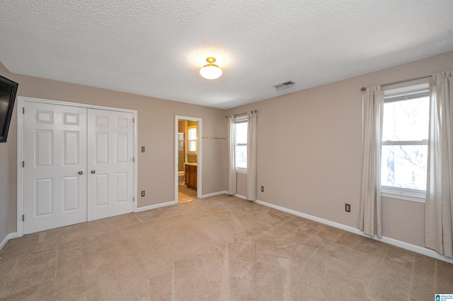 unfurnished bedroom featuring visible vents, light carpet, baseboards, and a closet