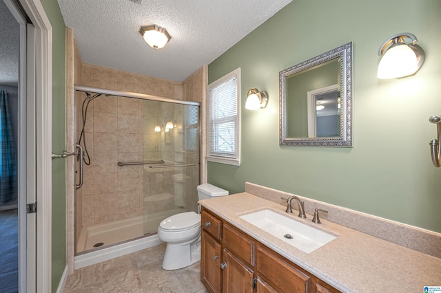 full bath featuring vanity, toilet, a stall shower, and a textured ceiling