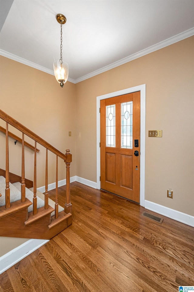 entryway featuring visible vents, ornamental molding, wood finished floors, baseboards, and stairs