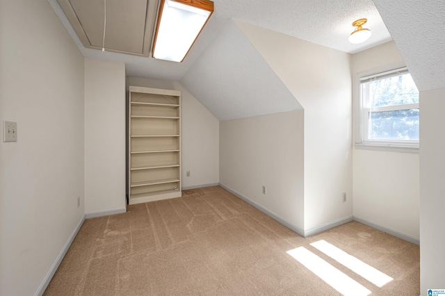 bonus room featuring light carpet, attic access, a textured ceiling, and baseboards