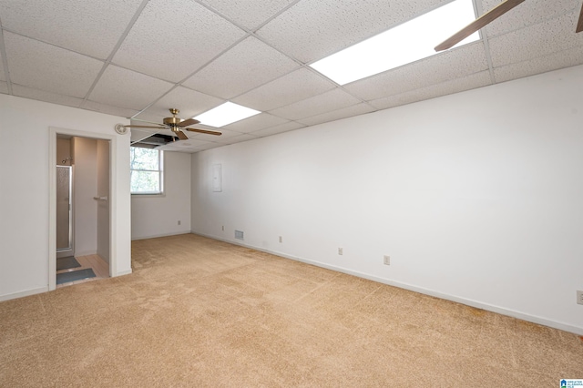 empty room featuring light carpet, a paneled ceiling, and a ceiling fan