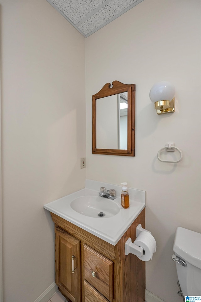 bathroom featuring baseboards, toilet, and vanity