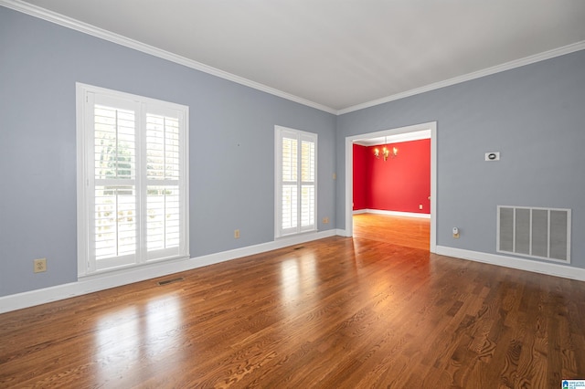 unfurnished room with a chandelier, visible vents, crown molding, and wood finished floors