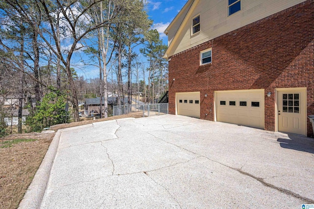 view of home's exterior featuring brick siding, driveway, and a garage