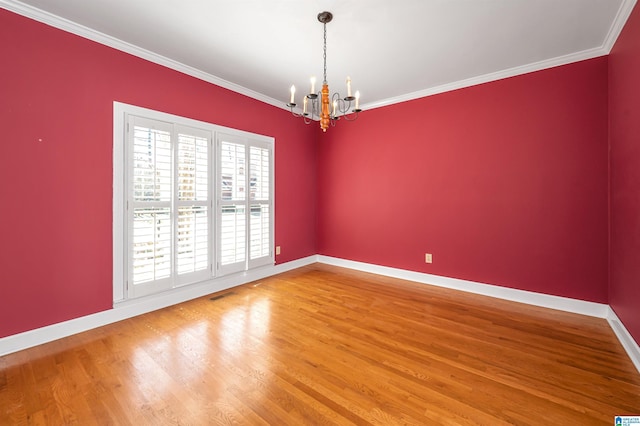 unfurnished room with visible vents, wood finished floors, crown molding, baseboards, and a chandelier