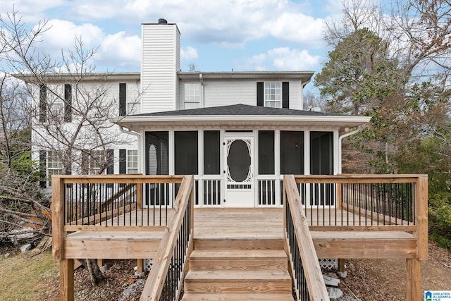 exterior space featuring a chimney, a shingled roof, a deck, and a sunroom