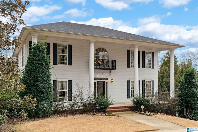 neoclassical home featuring a porch and roof with shingles