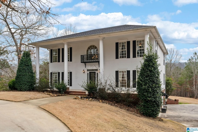 greek revival inspired property featuring a balcony and roof with shingles