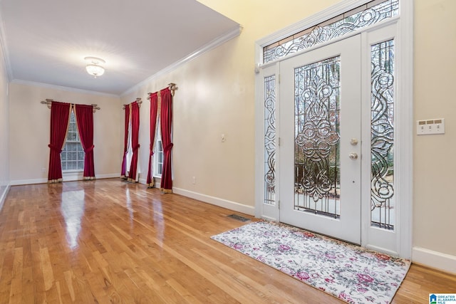 entryway with visible vents, wood finished floors, baseboards, and ornamental molding