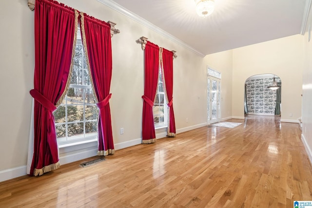 unfurnished room featuring crown molding, wood finished floors, visible vents, and baseboards