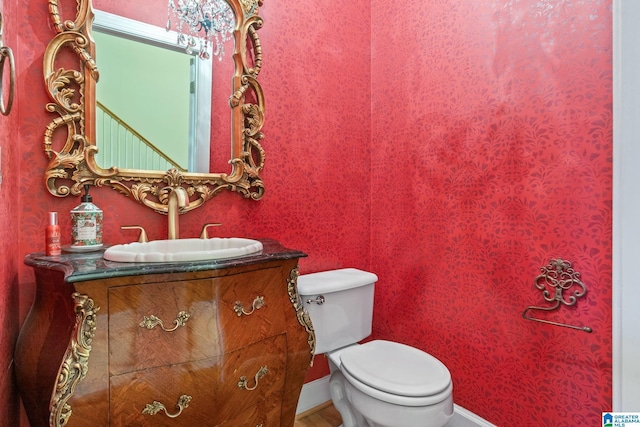 half bath with vanity, toilet, and baseboards