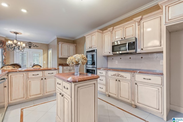 kitchen featuring light tile patterned floors, cream cabinetry, appliances with stainless steel finishes, and a center island