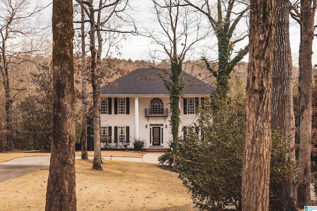 view of front facade featuring a balcony and a shingled roof