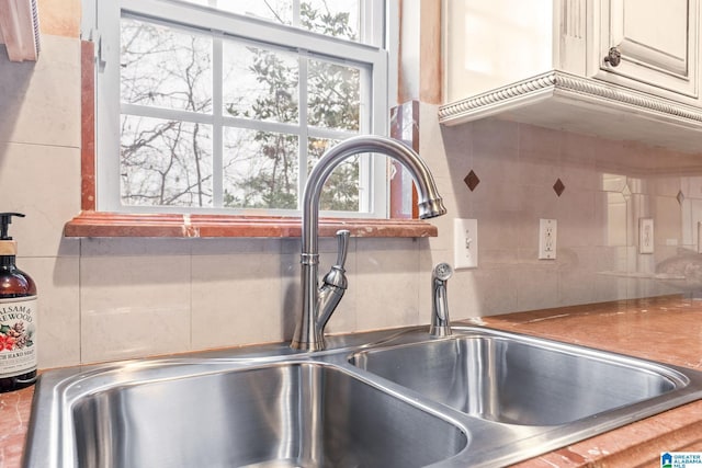 room details featuring backsplash, cream cabinets, and a sink