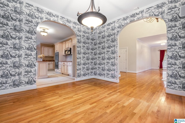 unfurnished dining area with arched walkways and wallpapered walls