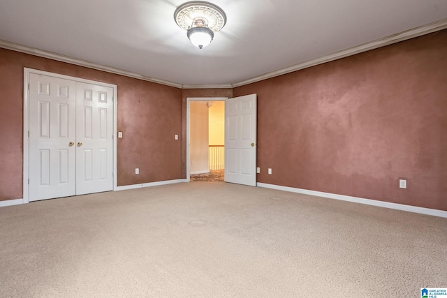 unfurnished bedroom featuring a closet, crown molding, baseboards, and carpet floors