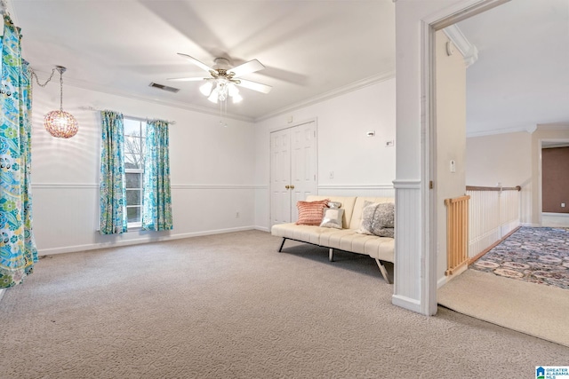 sitting room with a wainscoted wall, ceiling fan, crown molding, and carpet