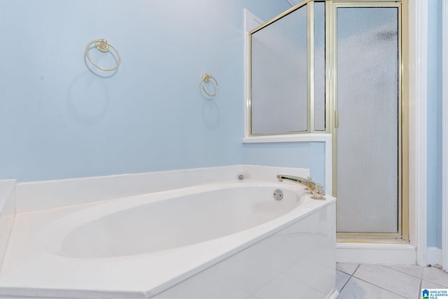 bathroom featuring tile patterned flooring, a bath, and a stall shower