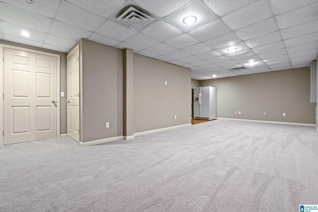 basement featuring fridge with ice dispenser, carpet, visible vents, and baseboards