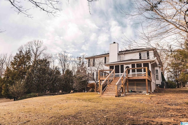 rear view of property with stairway, a lawn, a chimney, and a deck