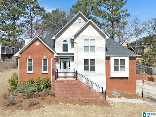 traditional home featuring brick siding and a shingled roof