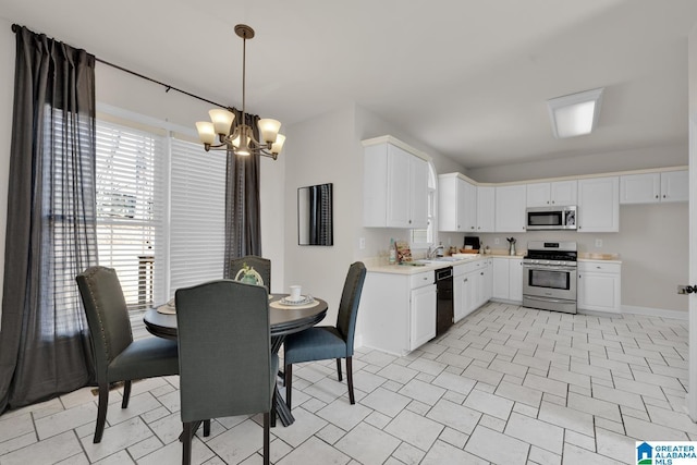 kitchen featuring a sink, stainless steel appliances, light countertops, white cabinetry, and a notable chandelier