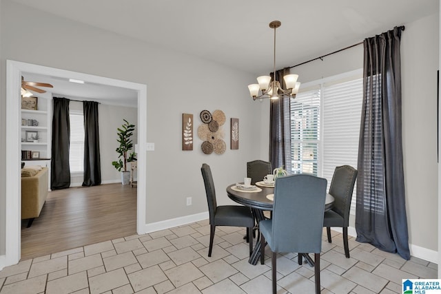 dining room featuring ceiling fan with notable chandelier and baseboards