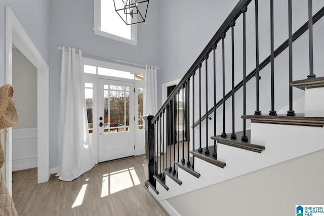 entrance foyer with plenty of natural light, stairway, an inviting chandelier, and wood finished floors