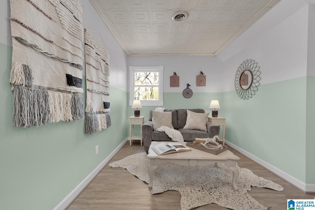 living area featuring visible vents, light wood-style flooring, crown molding, and baseboards