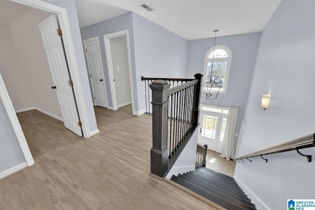 staircase featuring visible vents, baseboards, an inviting chandelier, and wood finished floors