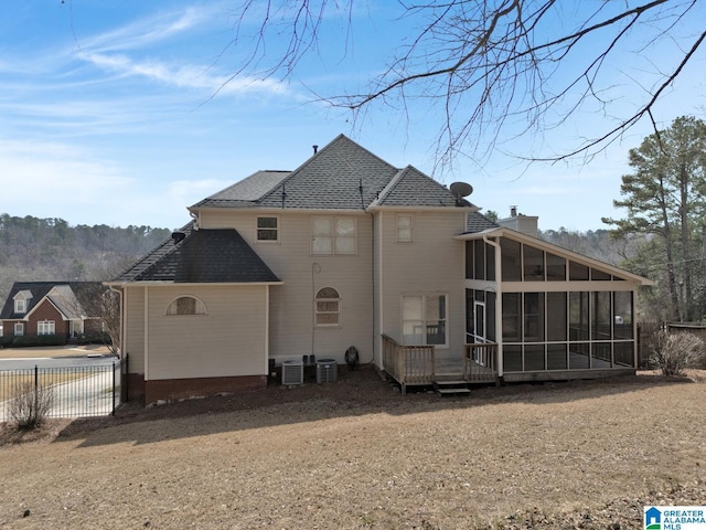 rear view of house featuring cooling unit, fence, a chimney, and a sunroom