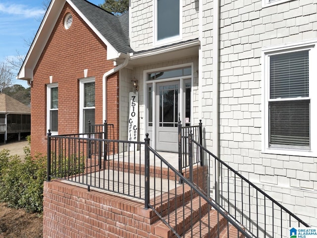 property entrance featuring brick siding and a shingled roof