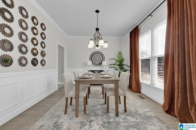 dining space with a wealth of natural light, light wood finished floors, an inviting chandelier, and ornamental molding