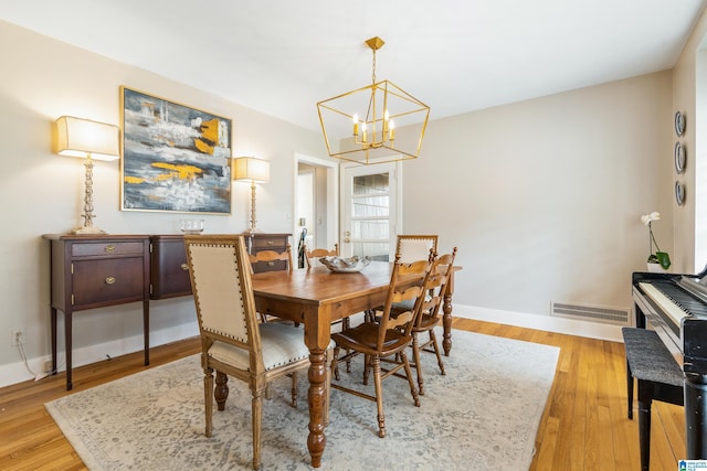 dining room featuring a chandelier, visible vents, baseboards, and light wood-style floors