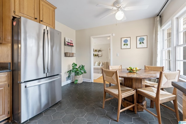 dining area featuring dark tile patterned floors, baseboards, and ceiling fan