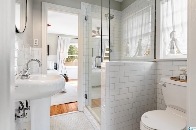 bathroom featuring toilet, a stall shower, ensuite bath, tile walls, and tile patterned flooring