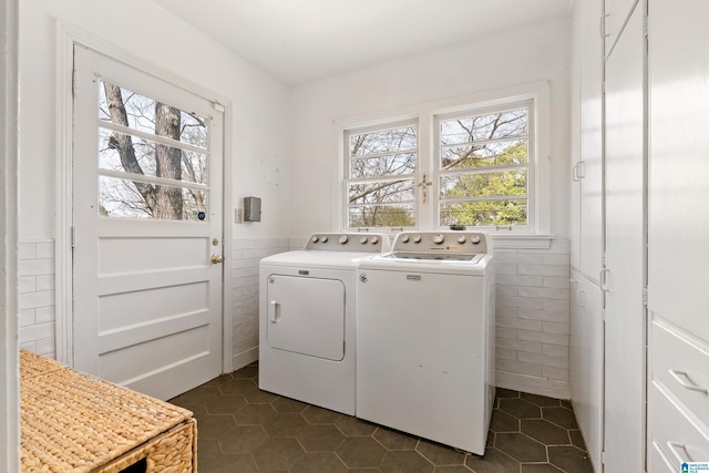 laundry room featuring a wainscoted wall, laundry area, separate washer and dryer, and tile walls