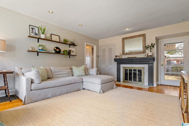 living area featuring a fireplace with flush hearth, recessed lighting, and wood finished floors