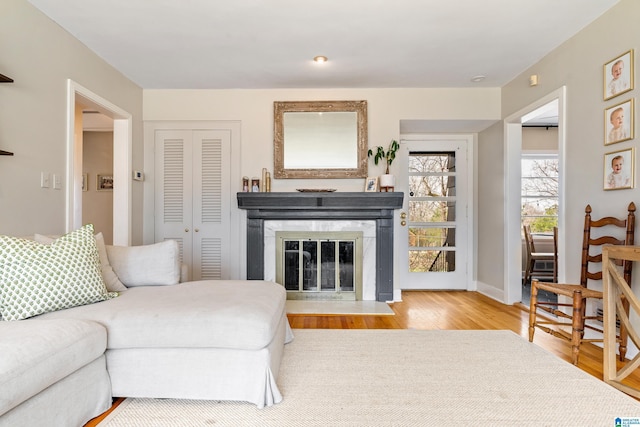 living area with a fireplace with flush hearth, baseboards, and wood finished floors