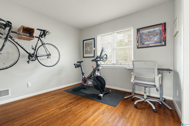 workout area featuring visible vents, baseboards, and wood finished floors