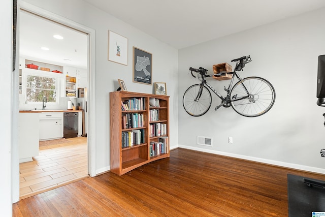 interior space featuring a sink, wood finished floors, visible vents, and baseboards