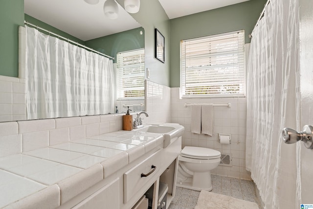 bathroom featuring a wainscoted wall, toilet, vanity, a shower with curtain, and tile walls