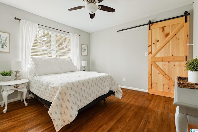 bedroom with dark wood finished floors, baseboards, a barn door, and a ceiling fan